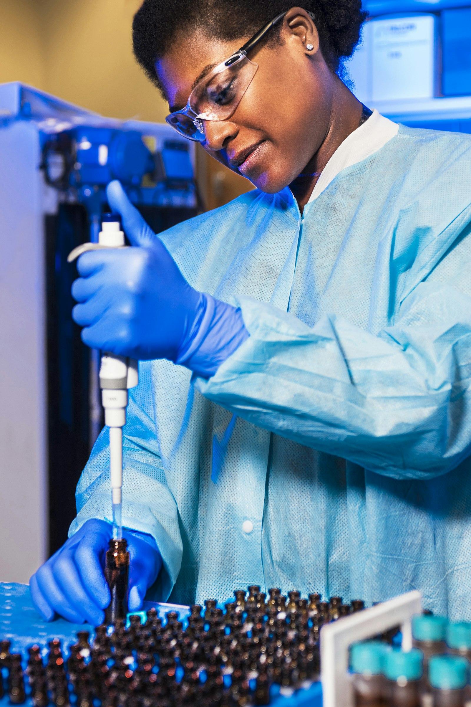 Lab technician pipetting into rows of sample vials